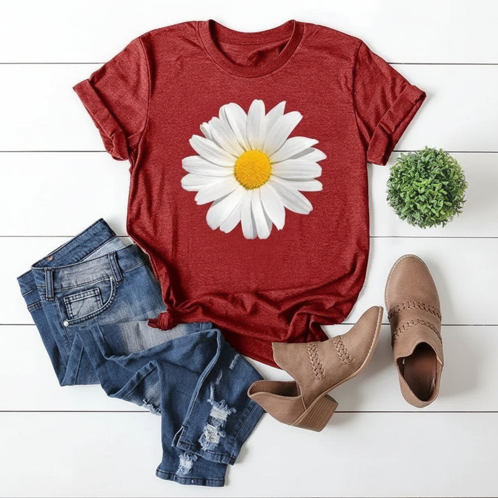 Red t-shirt with a white daisy graphic, paired with denim shorts and brown ankle boots on a white wooden surface.
