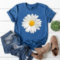 Blue t-shirt with a daisy graphic, paired with denim shorts and brown boots on a white wooden surface.