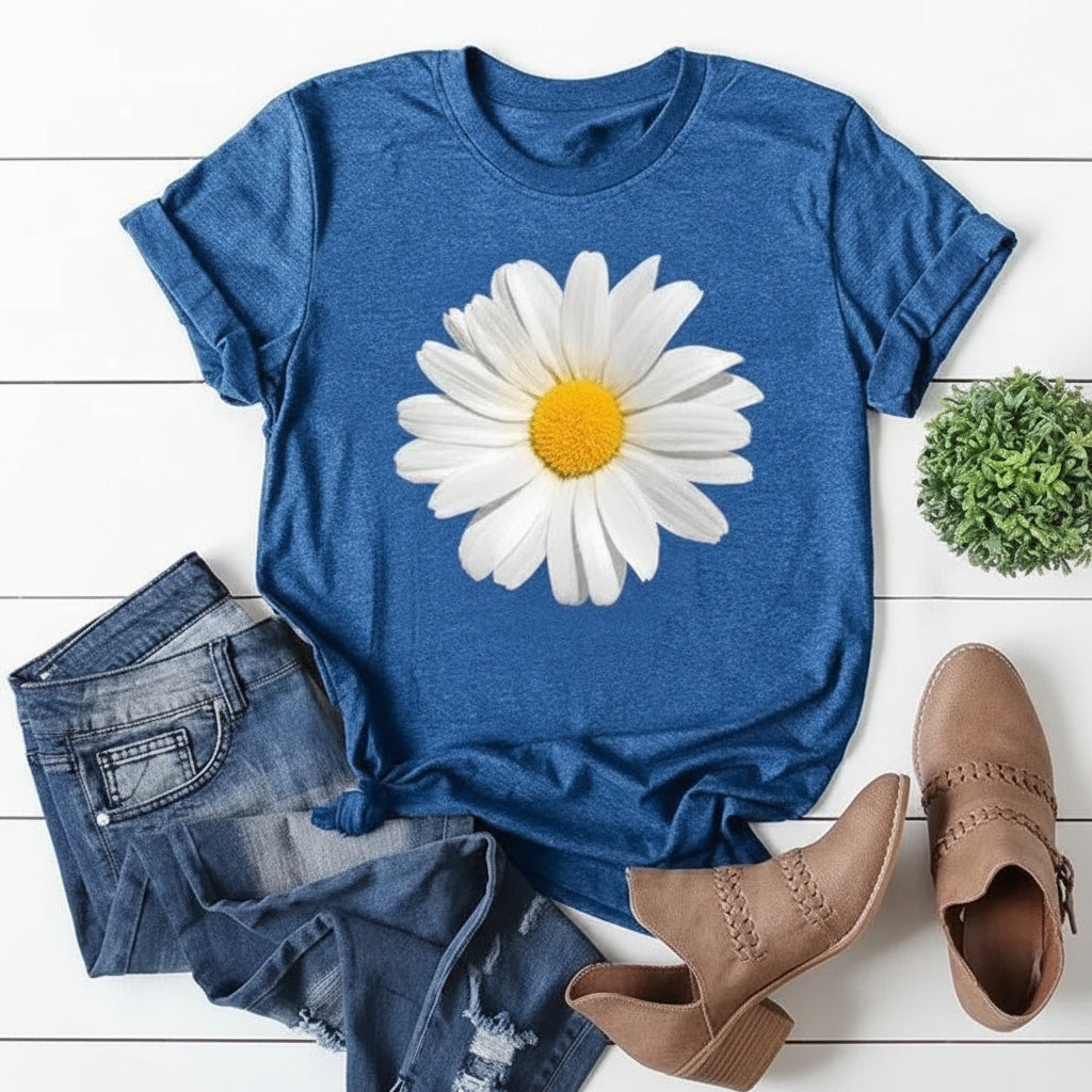 Blue t-shirt with a daisy graphic, paired with denim shorts and brown boots on a white wooden surface.