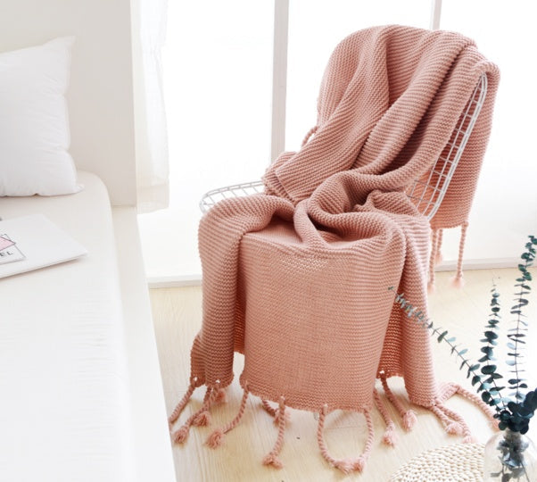 Pink blanket draped over a chair in a bright room