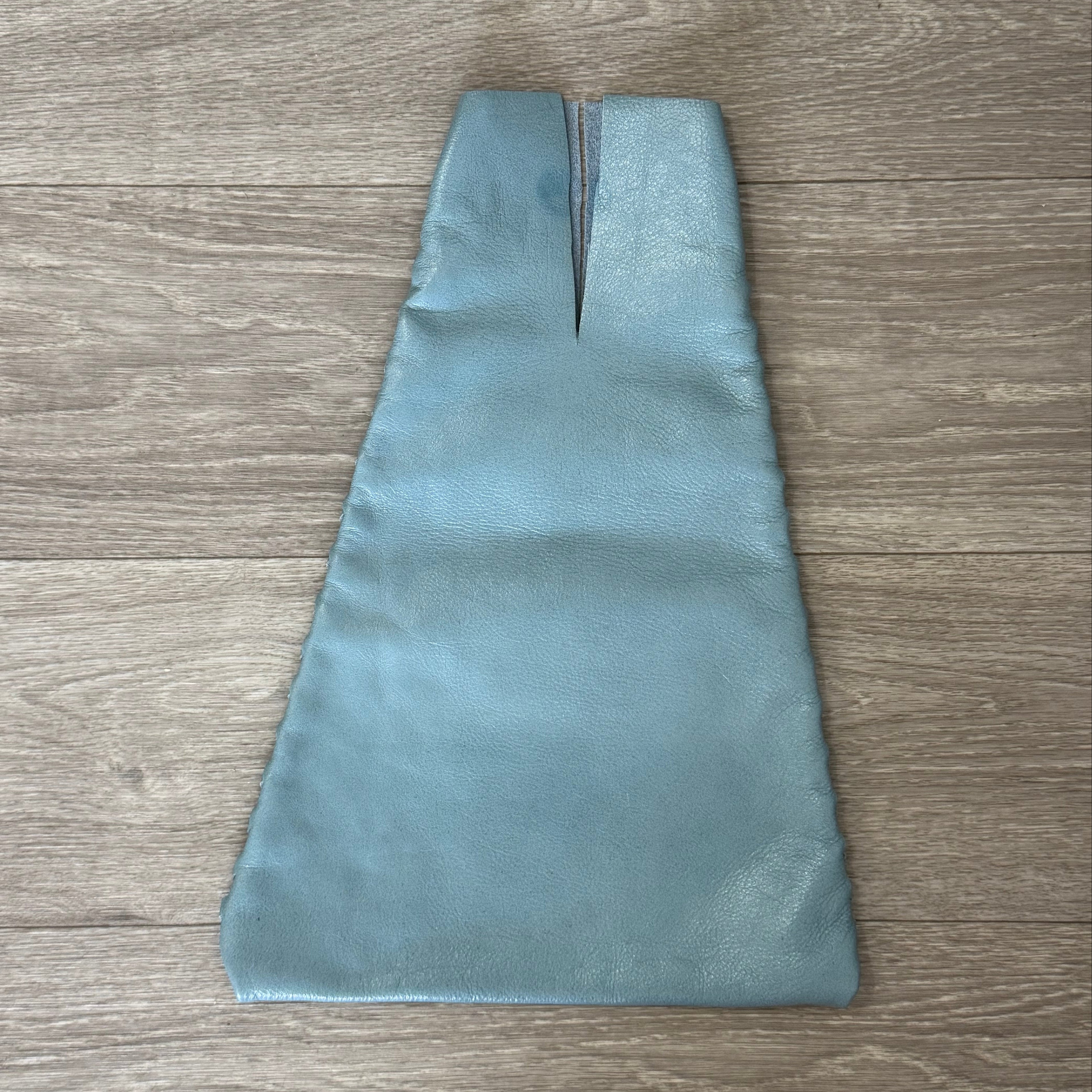 Blue open top leather bag on a wood surface.