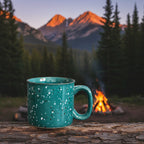 Teal mug on a wooden stump in front of a campfire with mountains in the background