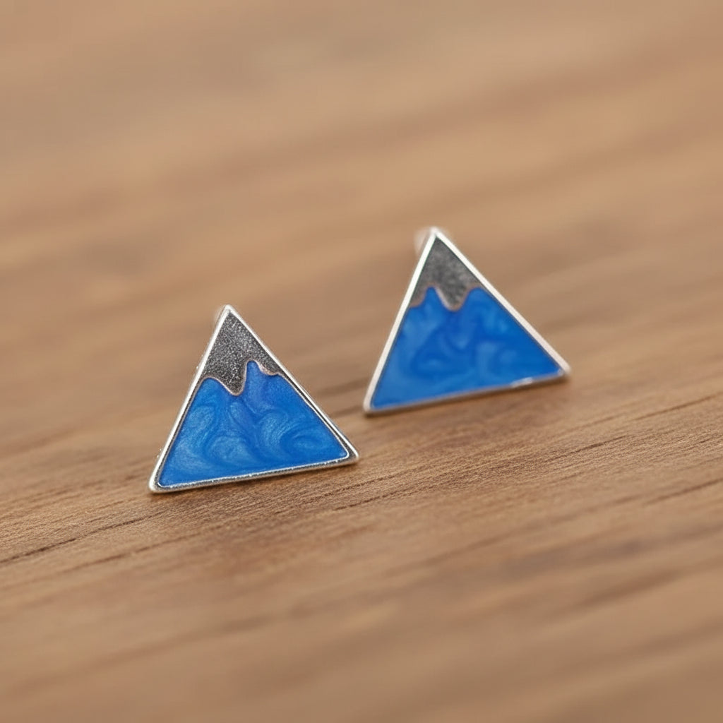 Triangle mountain earrings on a wooden background.
