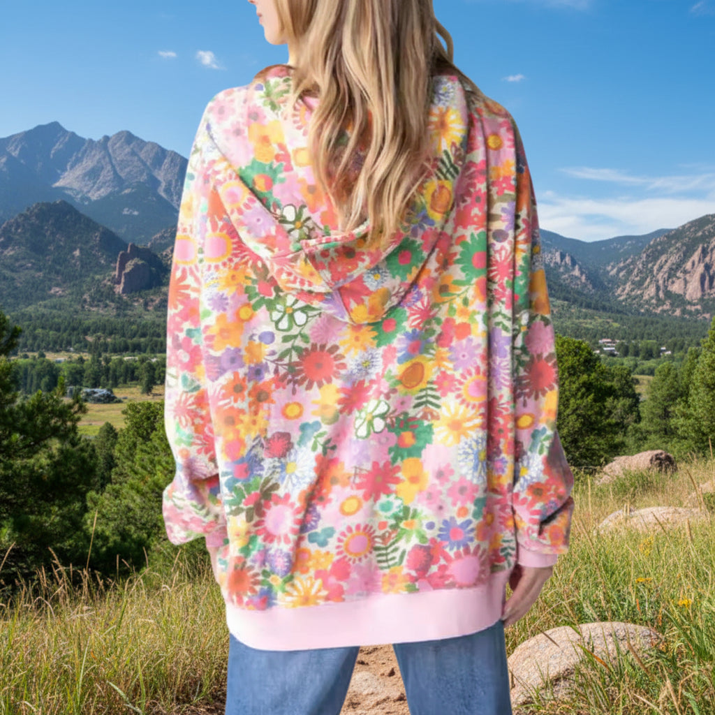 Person wearing a colorful floral hoodie with a Colorado Mountain background.