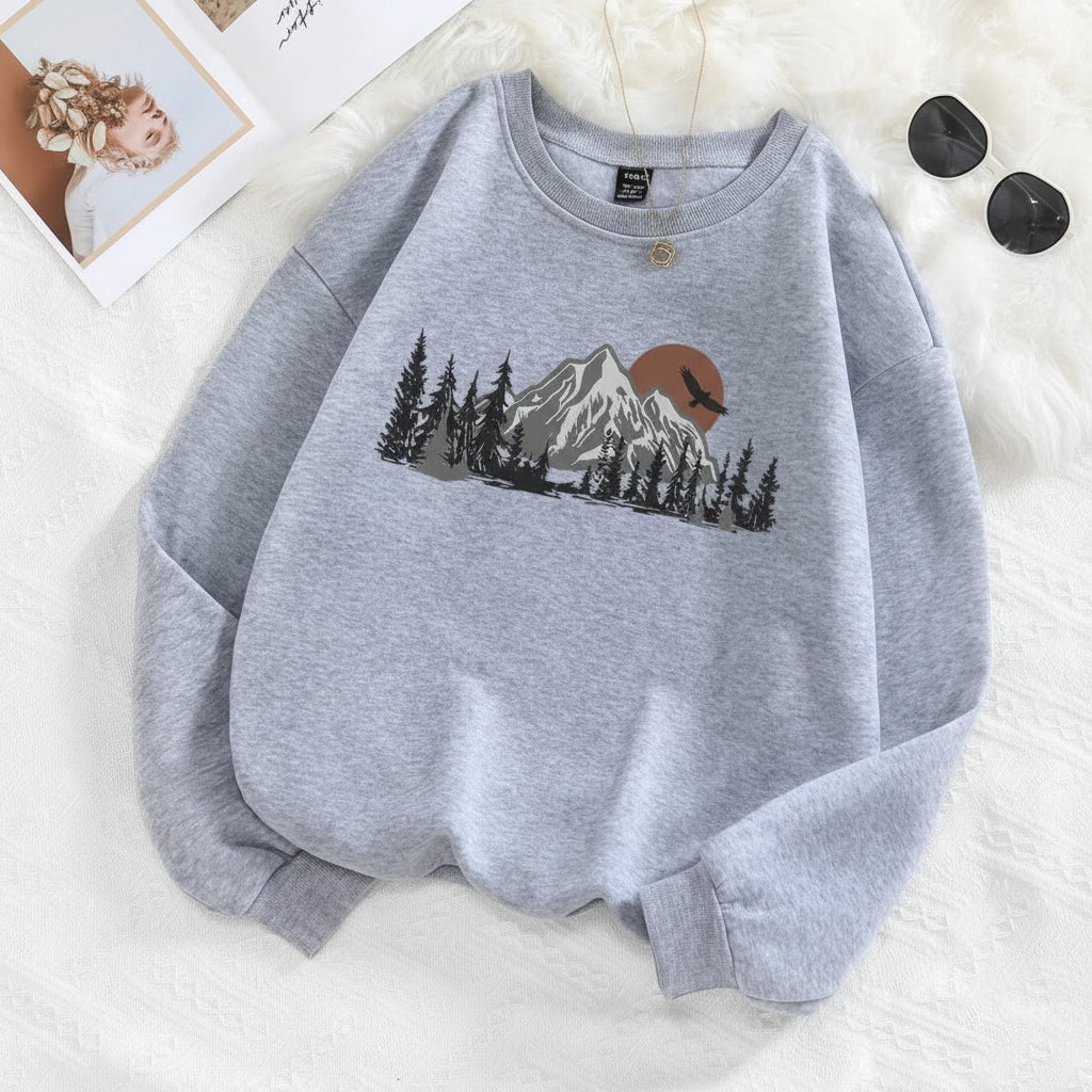 Gray sweatshirt with mountain and tree design on a white surface