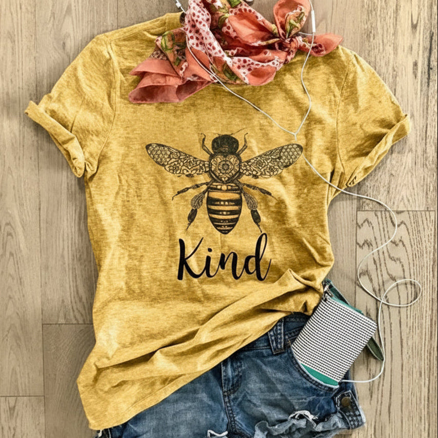 Yellow t-shirt with bee and 'Kind' text on a wooden surface