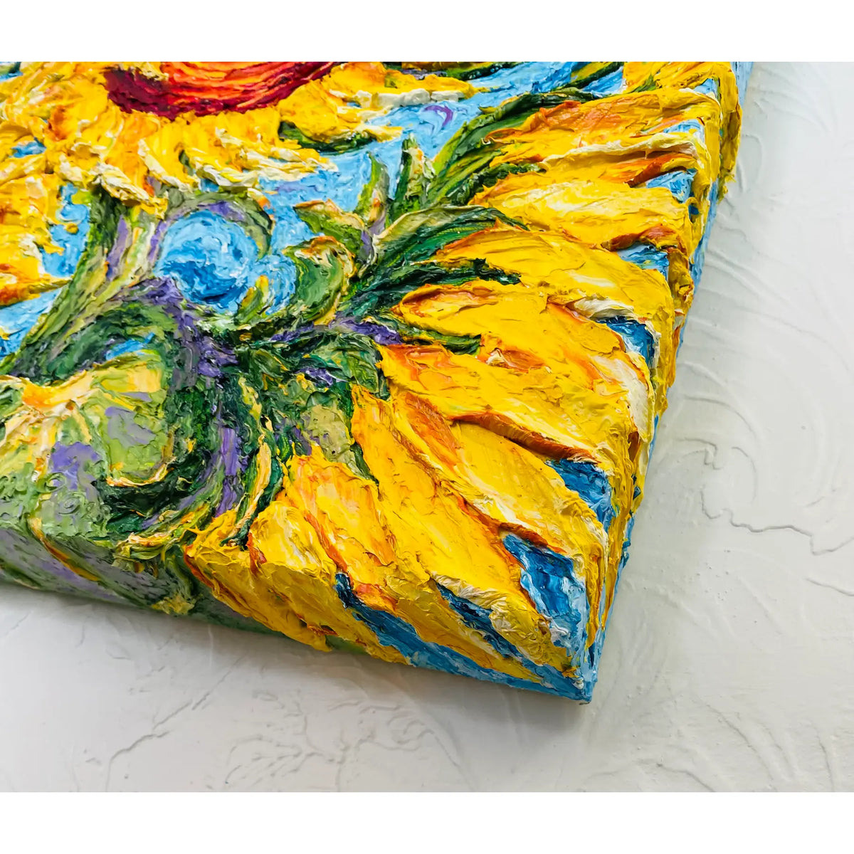 Close-up of thick yellow impasto petals and a painted canvas corner