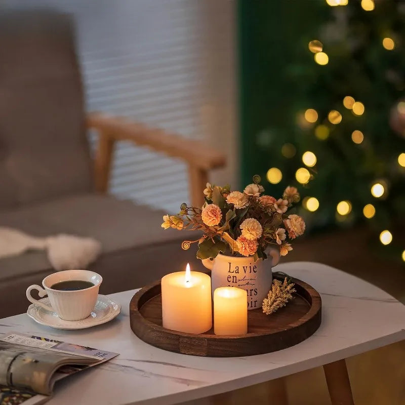 Tray with candles, flowers, and a cup on a table with a blurred Christmas tree in the background